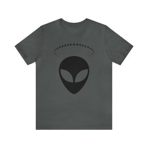 May include: A dark gray t-shirt with a black alien head graphic and a circle of stars above it.