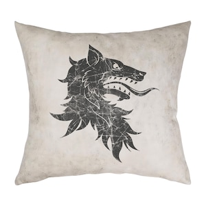 Puede incluir: Una almohada blanca con un diseño de cabeza de lobo en blanco y negro. El lobo está gruñendo con la boca abierta y la lengua fuera. La almohada tiene un aspecto desgastado y vintage.