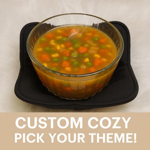 Puede incluir: Un cuenco de vidrio lleno de sopa de verduras humeante, sobre un salvamanteles negro. La sopa contiene zanahorias, guisantes y ma&iacute;z. El texto en la parte inferior dice: CUSTOM COZY PICK YOUR THEME!