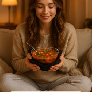 Puede incluir: Un cuenco de vidrio transparente lleno de sopa caliente, sostenido en un soporte de tela negra. La sopa contiene verduras visibles. La imagen incluye el texto "PHOTO FOR REFERENCE - FABRIC/COLOR WILL VARY".