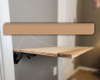Può includere: Uno scaffale in legno marrone chiaro con staffe in metallo nero fissate a una parete. Lo scaffale è ripiegato contro la parete.