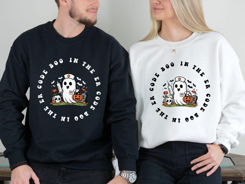May include: Black and white sweatshirt with a ghost wearing a nurse's hat and holding a syringe and a pumpkin. The text on the sweatshirt reads "Code Boo in the ER Code Boo in the ER".