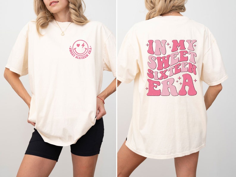 May include: A white t-shirt with a pink smiley face with a heart for an eye and a lightning bolt for a mouth. The text "Sweet Sixteen Era" is written around the smiley face. The back of the shirt has the text "In My Sweet Sixteen Era" written in pink with a retro font and stars.