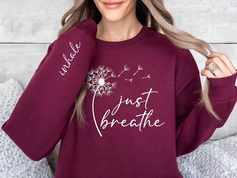 May include: Burgundy sweatshirt with a white dandelion graphic and the text "inhale just breathe".