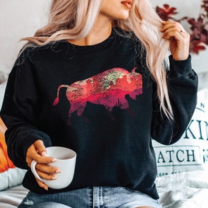May include: A black sweatshirt with a graphic print of a red, orange, and yellow bison silhouette against a sunset background.