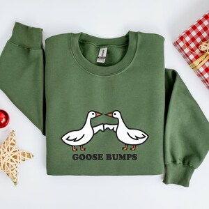 May include: A green sweatshirt with a white goose design and the text "GOOSE BUMPS".