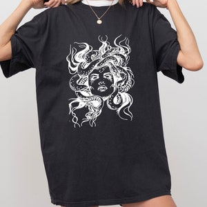 May include: Black t-shirt with a white graphic of Medusa's head with snakes.