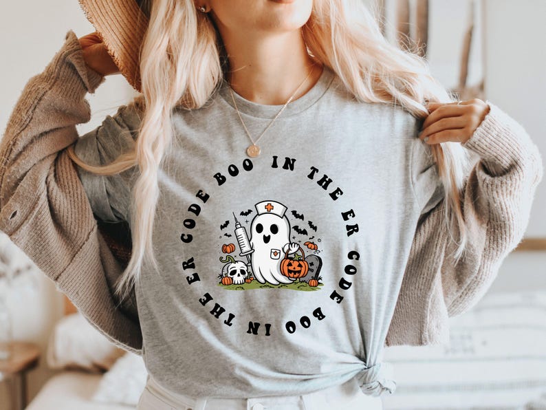 May include: A gray t-shirt with a black and white graphic of a ghost wearing a nurse's hat and holding a syringe and a pumpkin. The text around the ghost reads "Boo Code in the ER Code Boo".