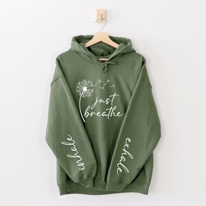 May include: A green hooded sweatshirt with the words "Just Breathe" and a dandelion graphic on the front. The words "inhale" and "exhale" are printed on the sleeves.