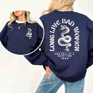 K&ouml;nnte beinhalten: Navyblauer Sweatshirt mit einem wei&szlig;en Schlangen-Motiv und dem Text "Long Live Bad Women" auf der R&uuml;ckseite. Der Text enth&auml;lt auch "One Hell of a Good Time 1993".