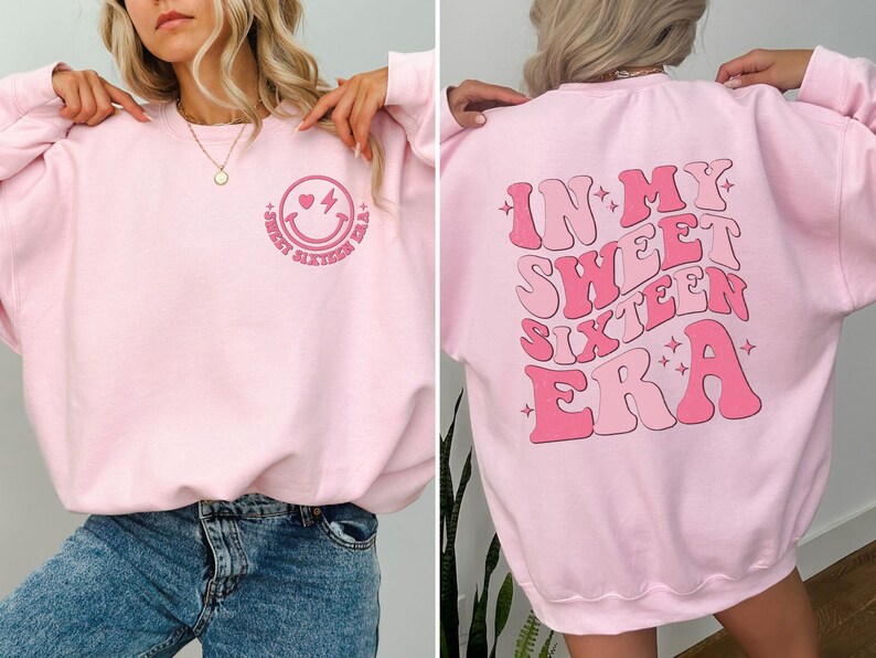 May include: Pink sweatshirt with a smiley face with a heart and lightning bolt on the front and the text "In My Sweet Sixteen Era" on the back.