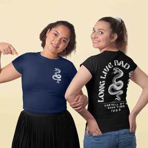 K&ouml;nnte beinhalten: Zwei Frauen tragen T-Shirts mit einem Schlangenmotiv. Das schwarze T-Shirt hat den Text "Long Live Bad" und "One hell of a good time 1993" auf der R&uuml;ckseite. Das marineblaue T-Shirt hat ein Schlangenmotiv auf der Vorderseite.