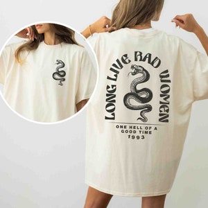 K&ouml;nnte beinhalten: Ein cremefarbenes T-Shirt mit einem schwarzen Schlangenmotiv und dem Text "Long Live Bad Women" auf der R&uuml;ckseite. Der Text enth&auml;lt auch "One hell of a good time 1993".