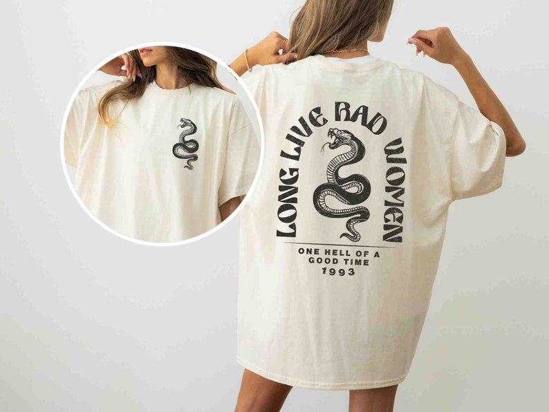 K&ouml;nnte beinhalten: Ein cremefarbenes T-Shirt mit einem schwarzen Schlangenmotiv und dem Text "Long Live Bad Women" auf der R&uuml;ckseite. Der Text enth&auml;lt auch "One hell of a good time 1993".