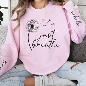 May include: Pink sweatshirt with a dandelion graphic and the text "just breathe". The sleeves have the words "inhale" and "exhale" printed on them.
