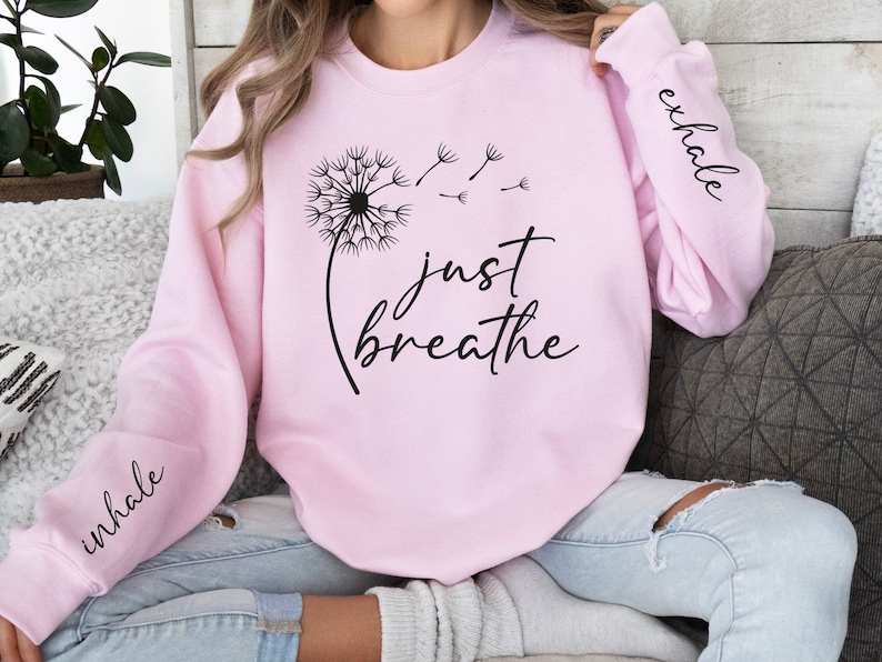 May include: Pink sweatshirt with a dandelion graphic and the text "just breathe". The sleeves have the words "inhale" and "exhale" printed on them.
