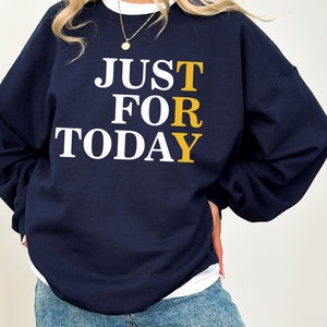 May include: A navy blue sweatshirt with the text "JUST FOR TODAY" in white and yellow letters.