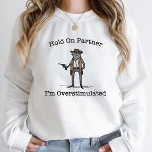 Hold On Partner Im Overstimulated Shirt, Cowboy Frog Sweatshirt, Unhinged Tshirt, Weirdcore Outfits, Gen Z Sweater, Funny Meme Hoodie Tee, Cowgirl Frog Women Sweatshirts, Western Frogs Girl Party Hoodies, Frog Gun Vacation Shirts,Holiday Cowgirls Tee