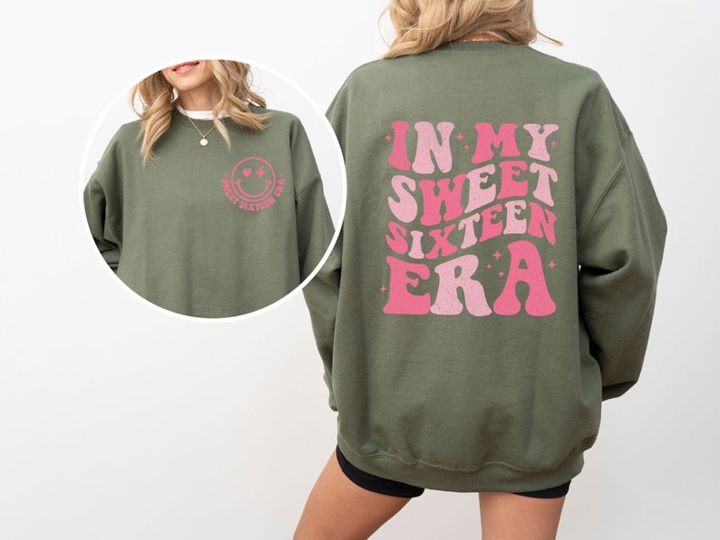May include: Green sweatshirt with a pink smiley face on the front and the text "In My Sweet Sixteen Era" in pink retro font on the back.