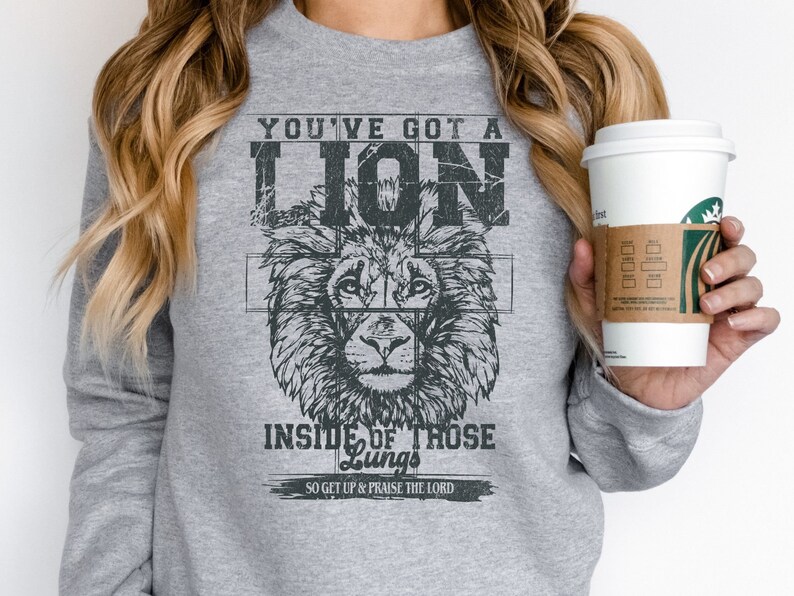 May include: Gray sweatshirt with a lion graphic and the text "You've got a lion inside of those lungs. So get up & praise the Lord."