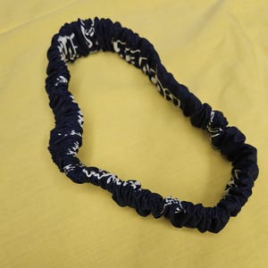 Pu&ograve; includere: Un cerchietto elastico blu navy con un motivo bianco.