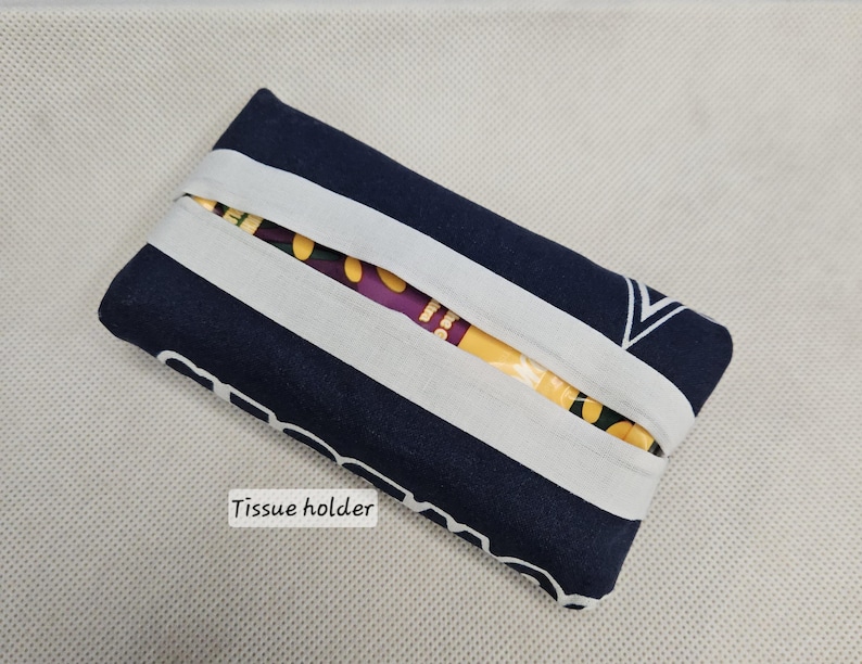 Pu&ograve; includere: Un porta fazzoletti a righe blu e bianche con la scritta "Tissue holder" stampata sul davanti.