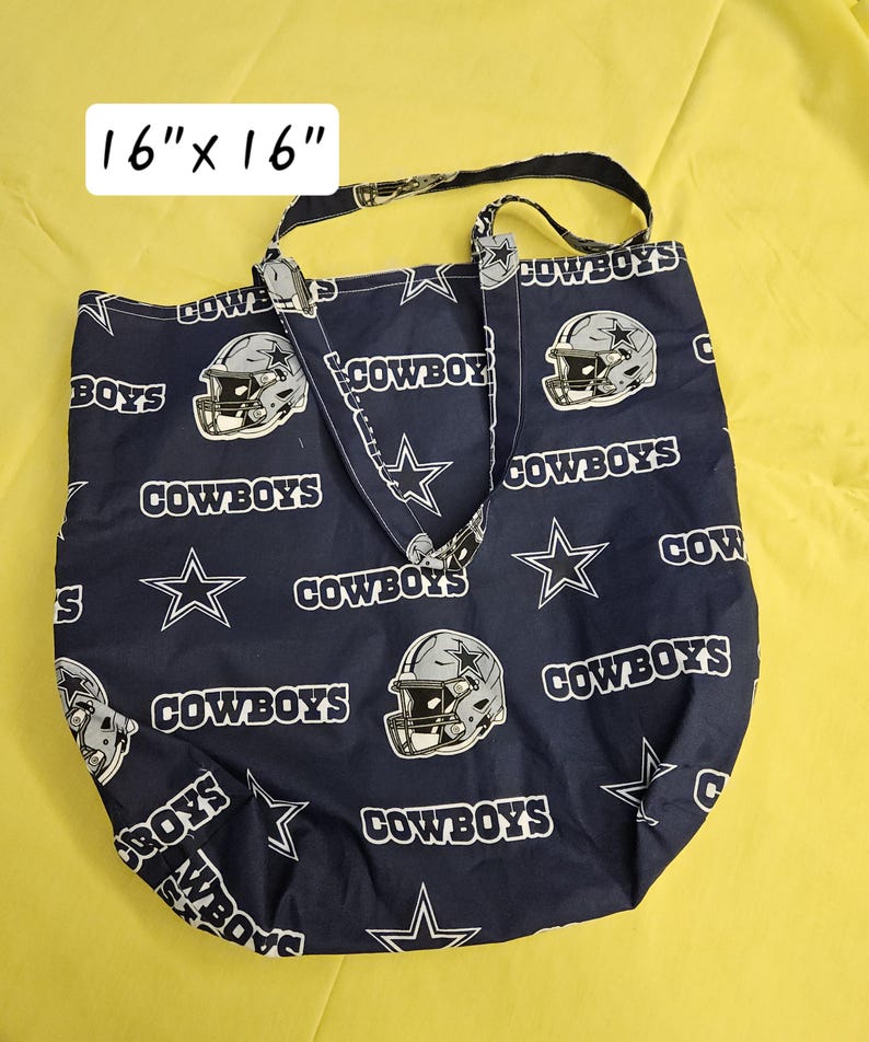 Pu&ograve; includere: Una borsa tote blu con un motivo a stella bianca e casco da football. La borsa ha due manici e dice "COWBOYS" ripetutamente. La borsa misura 16 pollici per 16 pollici.