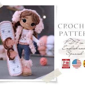 Puede incluir: Una muñeca de ganchillo con un chaleco forrado de piel sintética rosa, orejeras y botas, sosteniendo una tabla de snowboard blanca y rosa. La muñeca tiene cabello castaño y usa jeans azules. Incluye el texto "CROCHET PATTERN PDF in English and Spanish."
