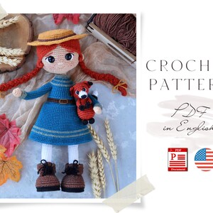 Puede incluir: Patrón de crochet PDF en inglés para una muñeca de pelo rojo con un sombrero marrón, un vestido azul y un peluche de zorro. La muñeca está rodeada de decoraciones de otoño como tallos de trigo y hojas de otoño.
