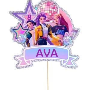 May include: A birthday cake topper with three animated figures, a disco ball, and star-shaped decorations. The topper has a banner reading "AVA" and the number "8". The design uses purple, pink, and silver glitter.