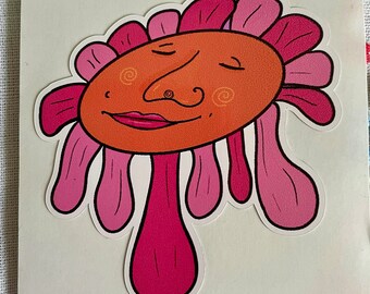 May include: A pink and orange cartoon face with closed eyes and a large nose. The face is surrounded by pink petals and has a pink stem.
