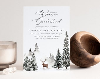 Könnte beinhalten: Eine Geburtstagseinladung mit Winterthema, mit Aquarellillustrationen eines Hirsches und Kiefern. Die Einladung lautet "Winter Onederland" und enthält Veranstaltungsdetails. Eine Kerze in einem Glas und eine Holzschale sind ebenfalls im Bild.