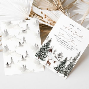 K&ouml;nnte beinhalten: Eine Babyparty-Einladung mit einem Winterwunderland-Thema. Die Einladung zeigt eine Aquarell-Illustration eines verschneiten Waldes mit einer H&uuml;tte und einem Reh. Der Text auf der Einladung lautet "Baby It's Cold Outside" und enth&auml;lt das Datum und die Uhrzeit der Party.