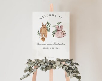 May include: A gender reveal sign on an easel. The sign reads "Welcome to Joanna and Michael's Gender Reveal" with illustrations of baby clothes. The sign is decorated with greenery and a date.