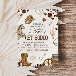 Puede incluir: Una invitaci&oacute;n blanca con ilustraciones de acuarela marr&oacute;n de un sombrero de vaquero, un cactus, una herradura, una rueda de carro y un par de botas de vaquero. El texto dice "Saddle Up & Ride On Over For Weston's 1st Rodeo" con la fecha y la hora del evento.