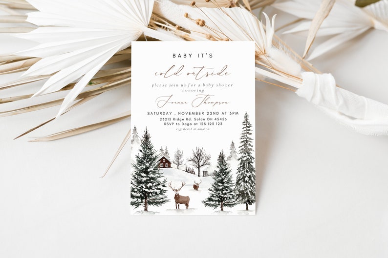K&ouml;nnte beinhalten: Eine Babyparty-Einladung im Winterwunderland mit einer verschneiten Waldszene, einer H&uuml;tte und Rehen. Der Text lautet "Baby It's Cold Outside" und enth&auml;lt Datum, Uhrzeit und Ort der Veranstaltung. RSVP an Dage unter 125 125 125.
