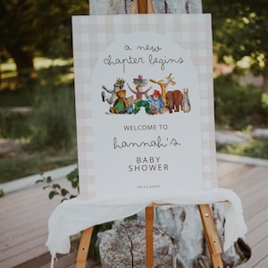 Könnte beinhalten: Ein rechteckiges Schild für eine Babyparty mit beigefarbenem und weißem Karomuster am Rand. Die Mitte zeigt ein Bogendesign mit dem Text "a new chapter begins" über Aquarellillustrationen von Märchenfiguren, "WELCOME TO Hannah's BABY SHOWER" und "10.12.20XX".