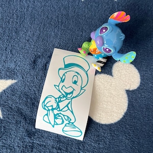 May include: A teal blue vinyl decal of a cartoon character wearing a top hat and holding a stick. The character is smiling and has a large, round head. The decal is on a white background.