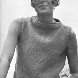 May include: A sleeveless, light-colored knit top with a high neckline. The top is worn with a white hat and sunglasses. The image is in black and white.