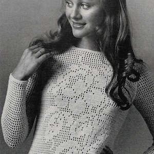 Peut inclure: Un haut en crochet crème à manches longues avec un motif floral. Le haut a une encolure ronde. Le design en crochet est ouvert et aéré, créant un aspect texturé. L'image est en noir et blanc.