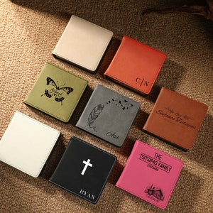 Puede incluir: Surtido de diez diarios de imitación de cuero personalizados con varios diseños y textos. Los diarios son de diferentes colores, incluyendo marrón, gris, negro, blanco y rosa. Los diseños incluyen una mariposa, una pluma, una cruz y una cabaña.
