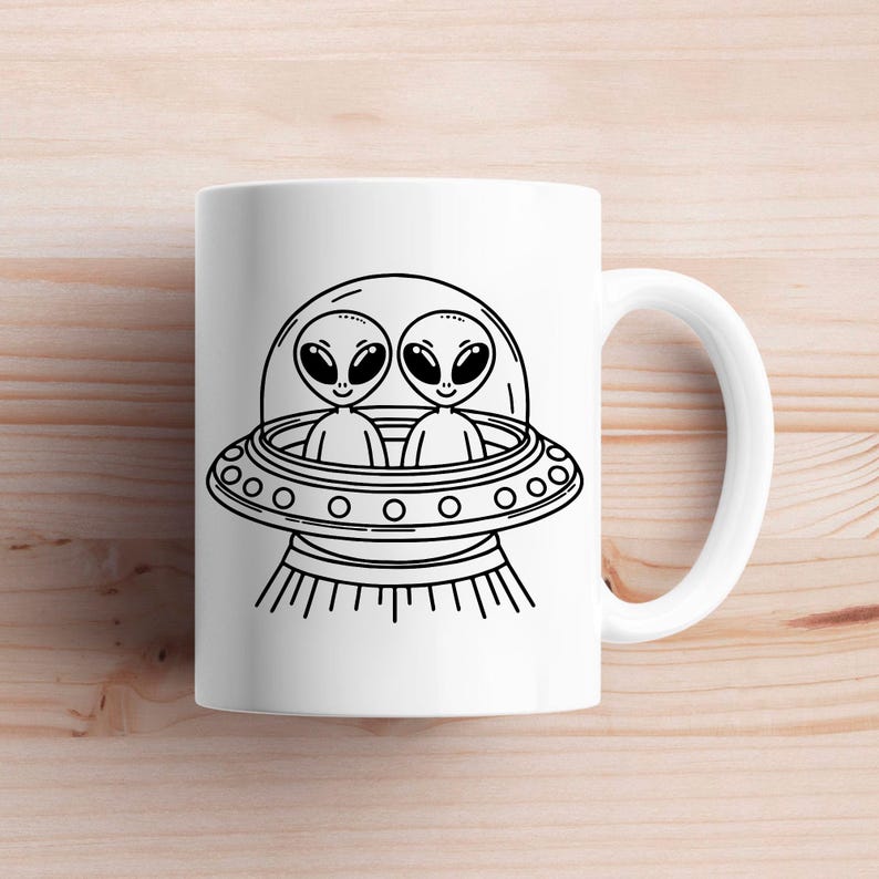 May include: White ceramic mug with a black and white illustration of two aliens in a flying saucer. The aliens have large eyes and are smiling.