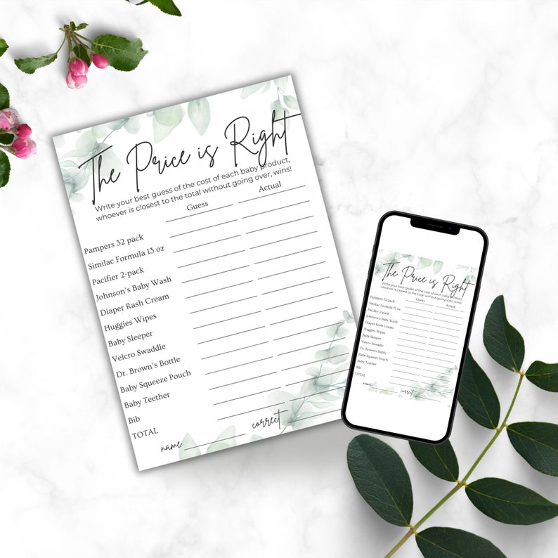 Green leaves on a white marble countertop. Baby shower The Price Is Right game 5x7 printout on the counter. Phone also on the counter with same Price is Right game displayed on it.