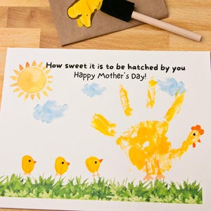 May include: A handmade Mother's Day card with a yellow handprint chicken design. The card features a sun, clouds, and three yellow chick footprints. The text reads, "How sweet it is to be hatched by you Happy Mother's Day!"