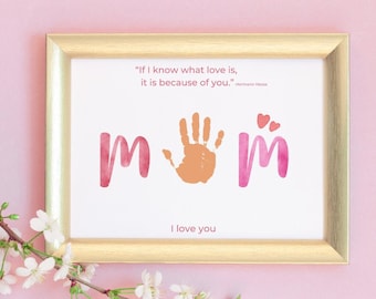 May include: A framed print with a gold-colored frame. The print features the word "mom" in watercolor style, with a handprint in the center. The quote "If I know what love is, it is because of you." is at the top, with "I love you" at the bottom.