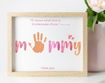 May include: A framed print with a handprint and the word "mommy" in pink and orange watercolor. The quote "If I know what love is, it is because of you." by Hermann Hesse is printed below the handprint. The print also includes the words "I love you".