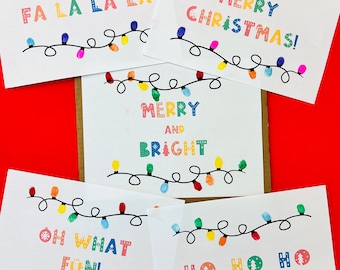 May include: Five Christmas cards with a string of colorful lights drawn on each card. The cards feature the following text: "Fa La La La", "Merry Christmas!" , "Merry and Bright", "Oh What Fun!" and "Ho Ho Ho".
