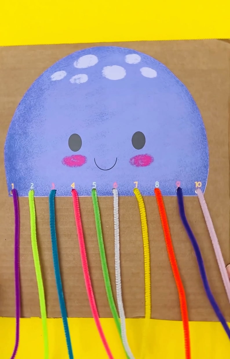 May include: A purple and white jellyfish craft with ten holes around the edge.  Each hole has a number from 1 to 10.  Ten colorful pipe cleaners are threaded through the holes.