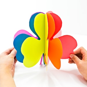 May include: A colorful paper shamrock with layers of blue, pink, yellow, orange, and red.