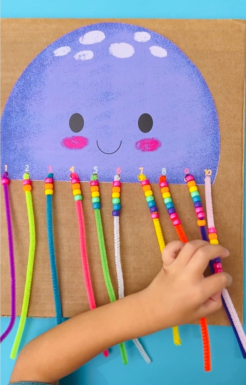 May include: A purple and white jellyfish craft with ten colorful pipe cleaner tentacles. Each tentacle has a string of colorful beads with numbers 1 through 10.